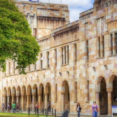 The sandstone buildings of UQ's Great Court with people wandering in the background.